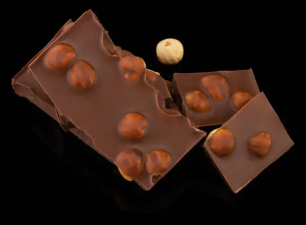 Pedaços de chocolate de leite com nozes em um fundo escuro — Fotografia de Stock