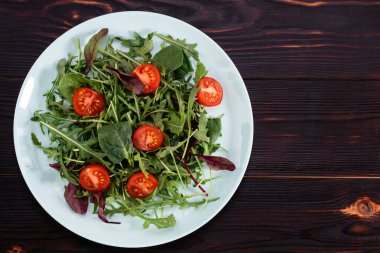 Arugula salatası ve ahşap arka planda domatesler. Yukarıdan görüntüle