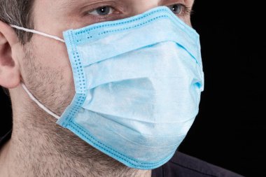 Siyah arka planda tıbbi maske takan hasta bir adamın portresi. Coronavirus konsepti.