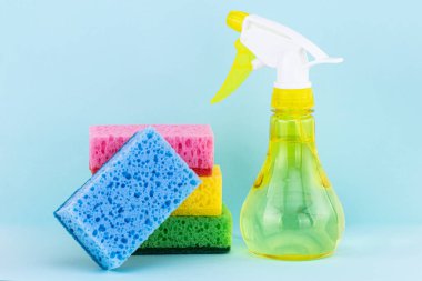 Bulaşık yıkamak için süngerler ve mavi arka planda sprey deterjan. Temizlik kavramı.