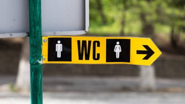 Tuvalet işaretçisi, wc oku, tuvalet ikonu, park sütununda yeşil metal işareti..