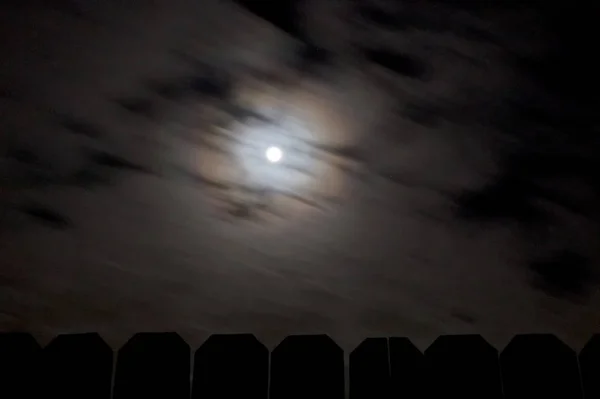 Яскравий повний місяць з швидкими хмарами над дерев'яним парканом — стокове фото