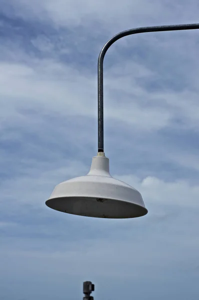 white metal light hanging in sky with clouds