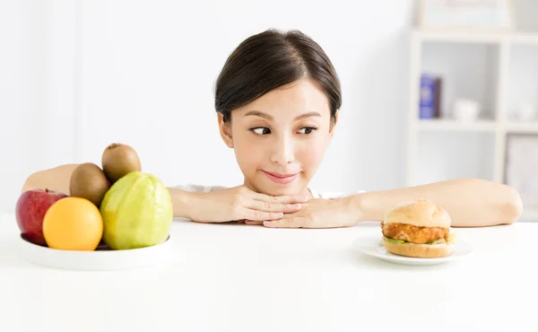 Young woman making choice between healthy and harmful food — Stock Photo, Image