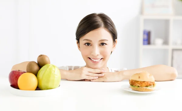 Молодая женщина делает выбор между здоровой и вредной пищей — стоковое фото