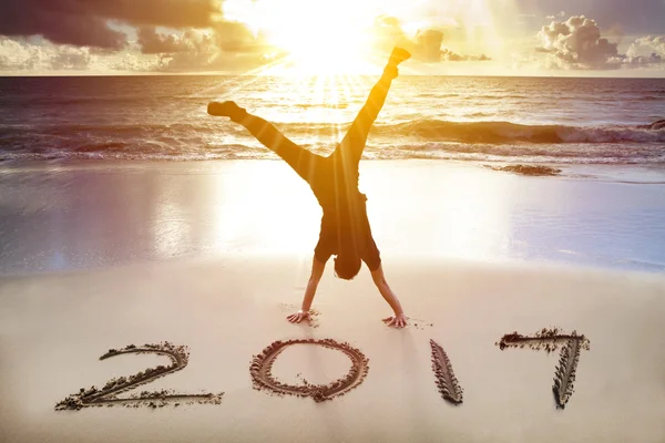 Junger Mann Handstand am Strand.Frohes neues Jahr 2017 Konzept — Stockfoto