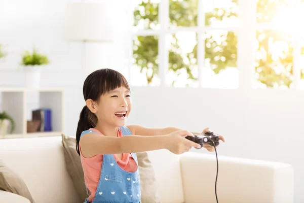 Śmiejąc się mała dziewczynka, grając w gry wideo na kanapie — Zdjęcie stockowe