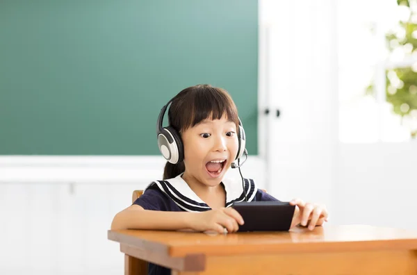 Niña feliz aprendizaje con el teléfono inteligente en el aula —  Fotos de Stock