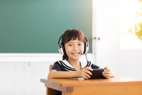 Glückliches kleines Mädchen lernt mit Smartphone im Klassenzimmer — Stockfoto