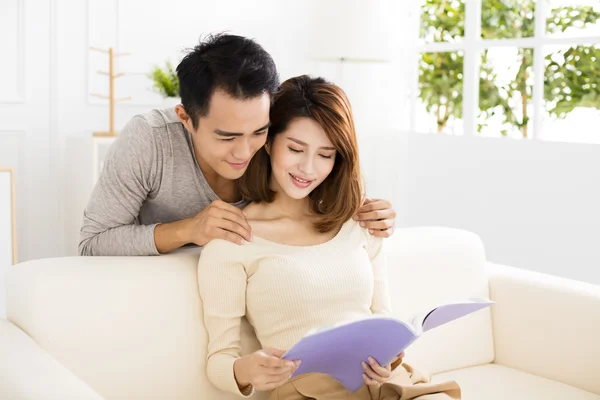 Pareja joven pasar tiempo leyendo juntos en el sofá —  Fotos de Stock