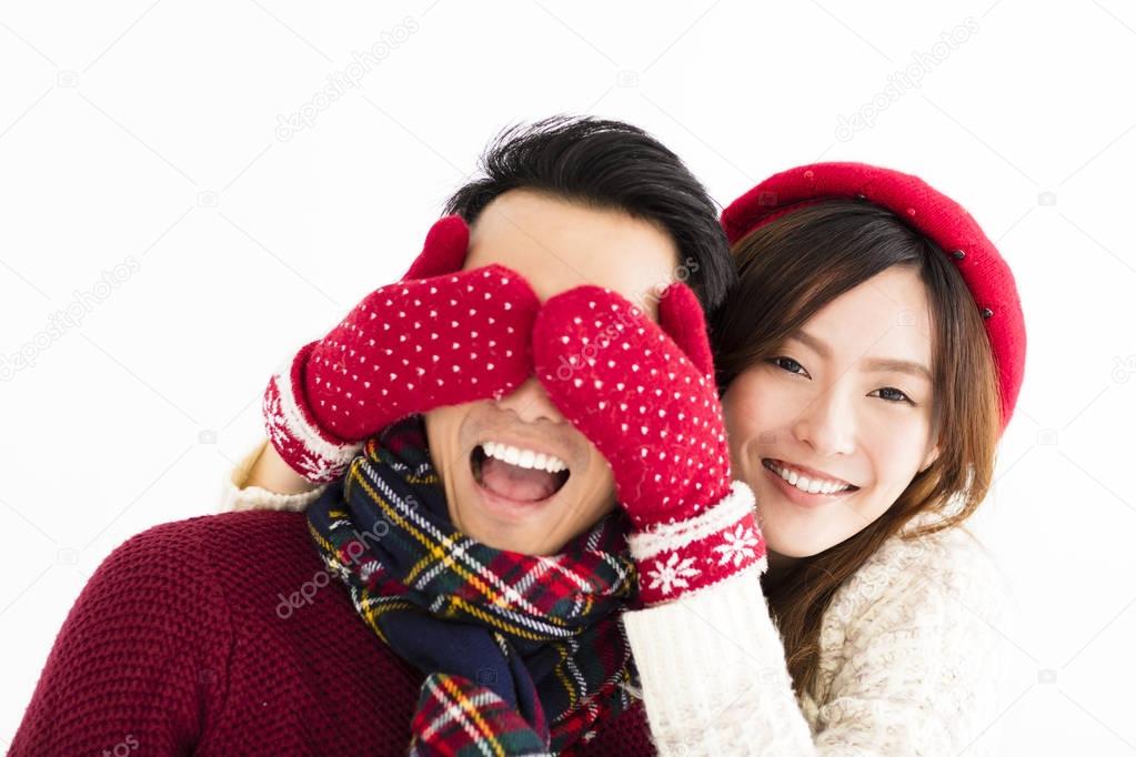 happy couple in winter wear and covering eyes to surprised 