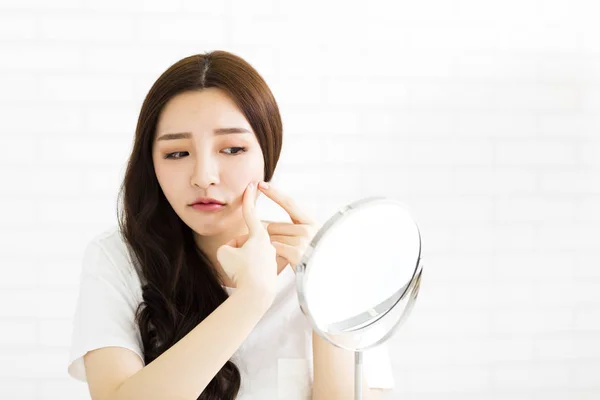 Jeune femme serrer son acné devant le miroir — Photo