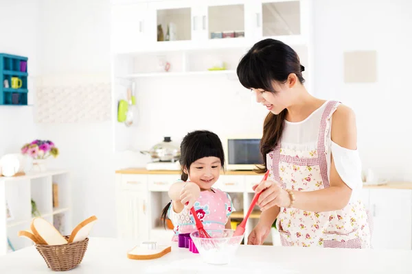 Mała dziewczynka, pomagając jej matka, przygotowywać posiłki w kuchni — Zdjęcie stockowe
