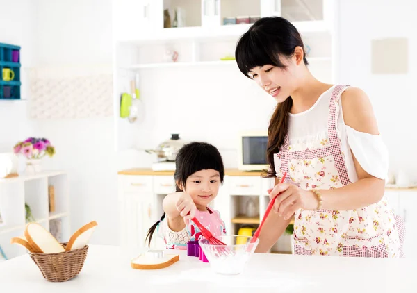 Mała dziewczynka, pomagając jej matka, przygotowywać posiłki w kuchni — Zdjęcie stockowe