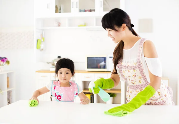 Petite fille aidant sa mère à nettoyer la table dans la cuisine — Photo