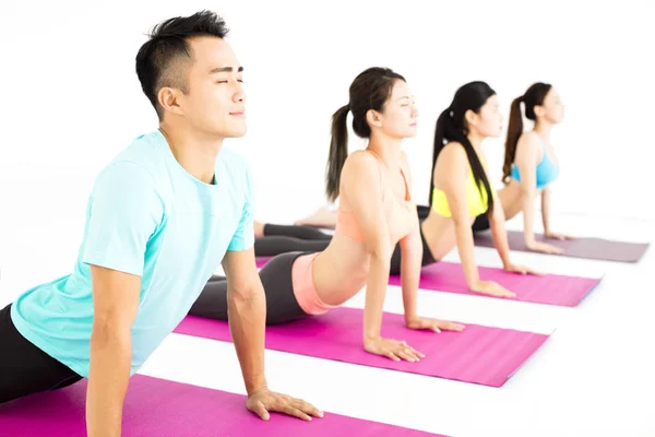 Fröhliche junge Gruppe macht Yoga-Übungen — Stockfoto