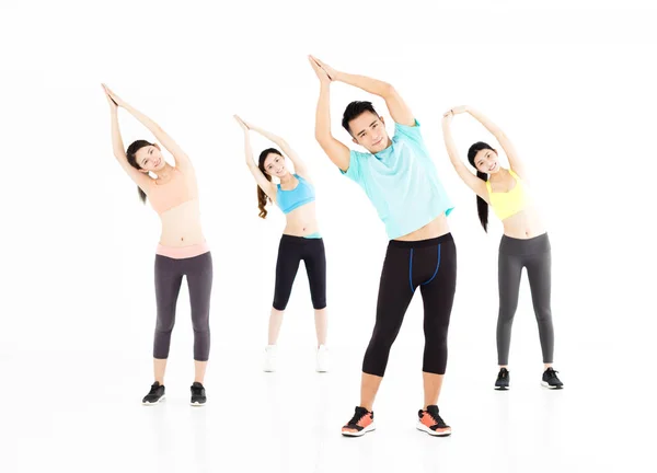 Sonriente joven en forma grupo estiramiento en el gimnasio — Foto de Stock