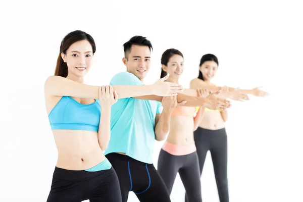 Sonriente joven en forma grupo estiramiento en el gimnasio — Foto de Stock