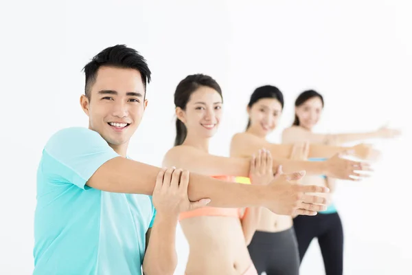 Lachende jonge passen groep die zich uitstrekt in sportschool — Stockfoto