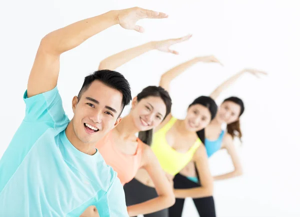 Smiling young fit group stretching in gym — Stock Photo, Image