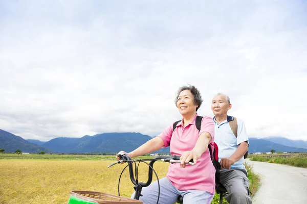 Щаслива старша пара їзда на велосипеді на заміській дорозі — стокове фото