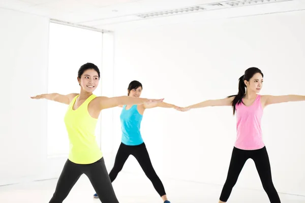 Sonriente joven grupo estiramiento en gimnasio — Foto de Stock