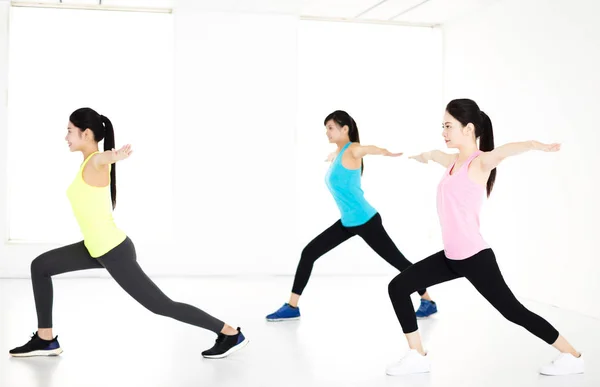 Sonriente joven grupo estiramiento en gimnasio — Foto de Stock