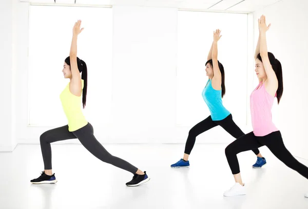 Sonriente joven grupo estiramiento en gimnasio —  Fotos de Stock