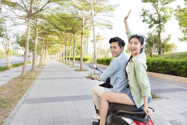 Feliz joven pareja a caballo scooter en la ciudad —  Fotos de Stock