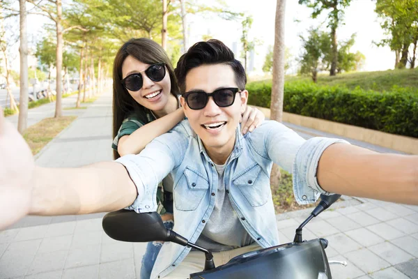 Feliz joven pareja a caballo scooter y hacer foto selfie — Foto de Stock