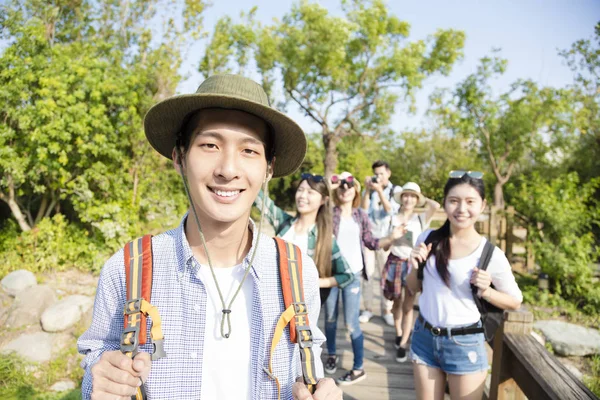 Grupo jovem feliz caminhadas juntos através da floresta — Fotografia de Stock