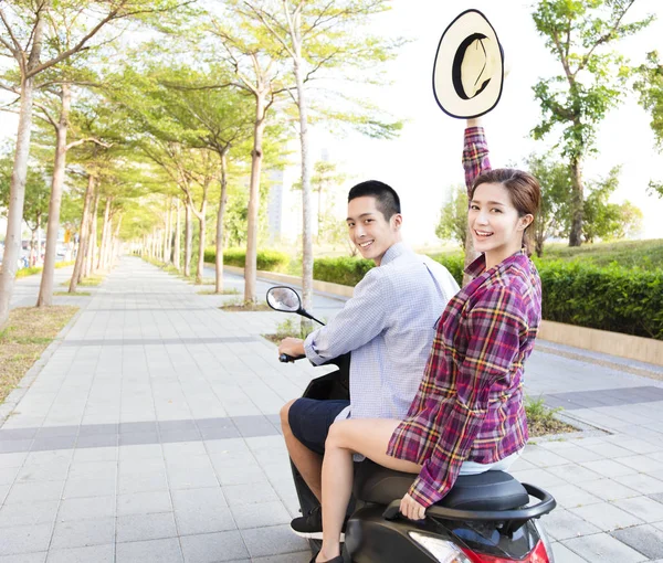 happy young couple riding  scooter in town