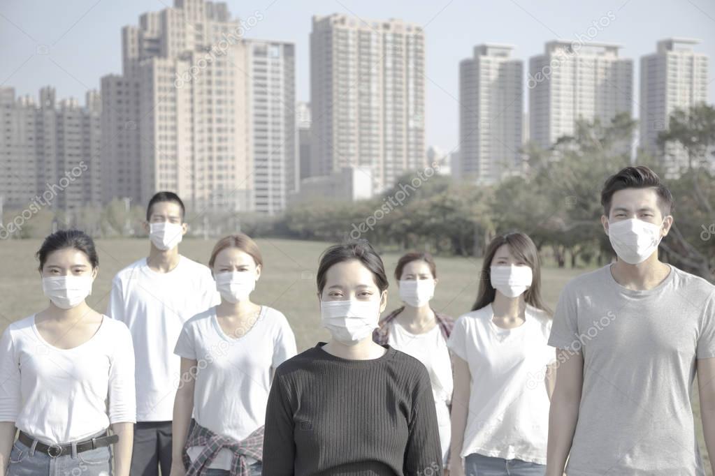 young group wearing mouth mask against air pollution in city