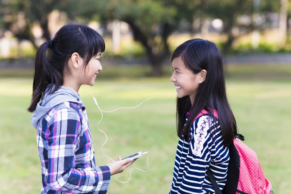 Zwei Freundinnen im Teenageralter beobachten das Smartphone in der Schule — Stockfoto