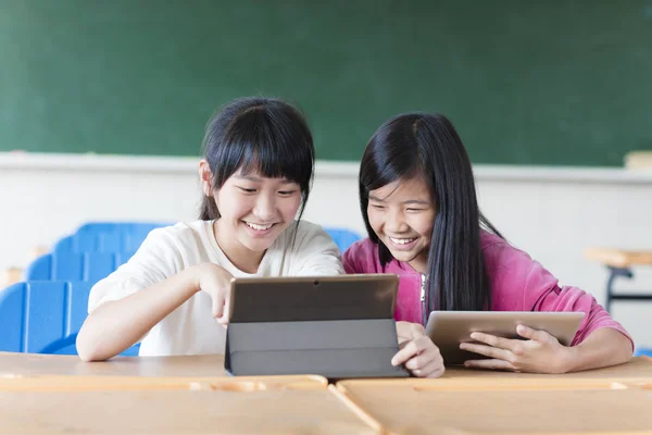 两个少女学生看教室里的这款平板电脑 — 图库照片