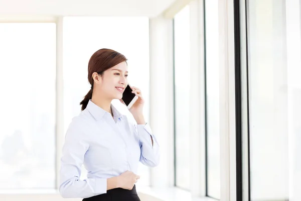 Sonriente mujer de negocios hablando por teléfono en la oficina —  Fotos de Stock