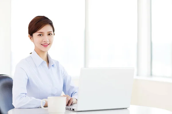 Jonge zakenvrouw met laptop in het kantoor — Stockfoto