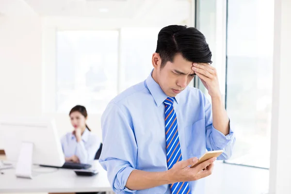 Estresado joven hombre de negocios mirando el teléfono inteligente —  Fotos de Stock