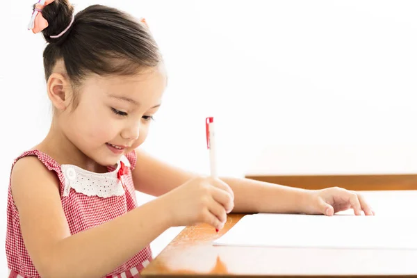 Niña feliz escribiendo en el escritorio en el aula — Foto de Stock