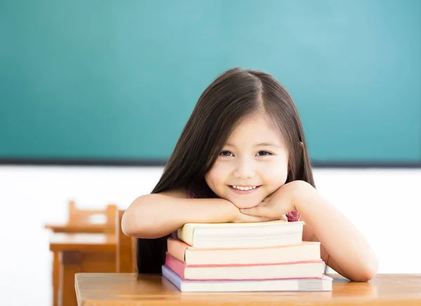 Gelukkig klein meisje met boeken in de klas — Stockfoto