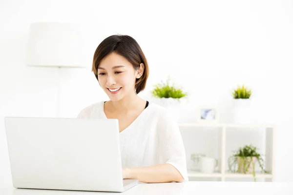 Gelukkig jonge vrouw met laptop in de woonkamer — Stockfoto