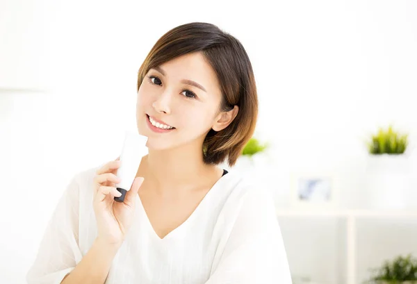Sonriente joven mujer mostrando productos para el cuidado de la piel — Foto de Stock