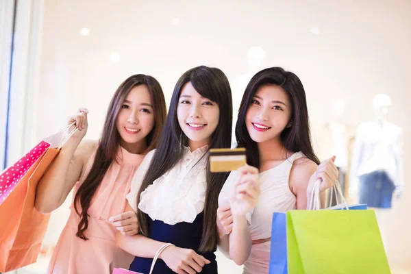 Grupo de mujeres felices sosteniendo bolsas de compras y tarjeta de crédito en el centro comercial —  Fotos de Stock