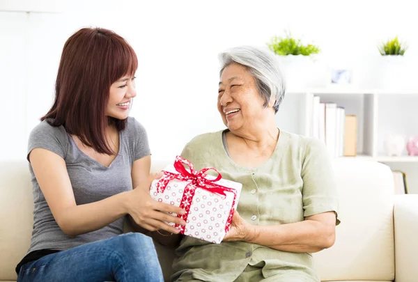 Счастливая молодая женщина дарит подарок бабушке — стоковое фото