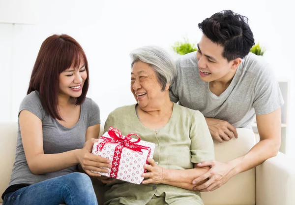 Pasangan muda yang bahagia memberikan hadiah untuk nenek — Stok Foto