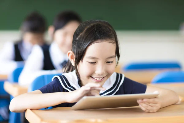 Leende liten flicka med hjälp av TabletPC i klassrummet — Stockfoto