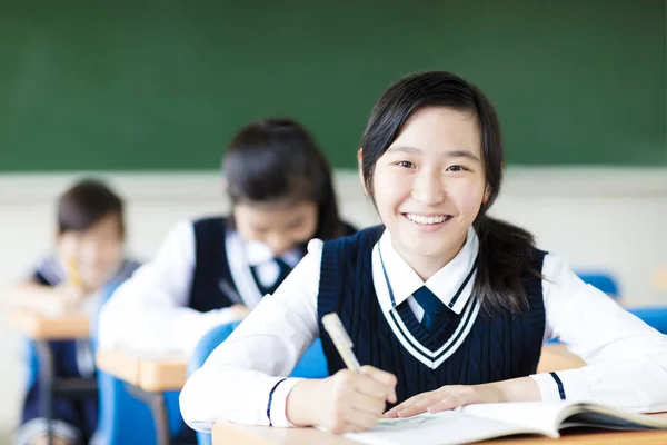 Sorrindo menina estudante em sala de aula e seus amigos no fundo — Fotografia de Stock