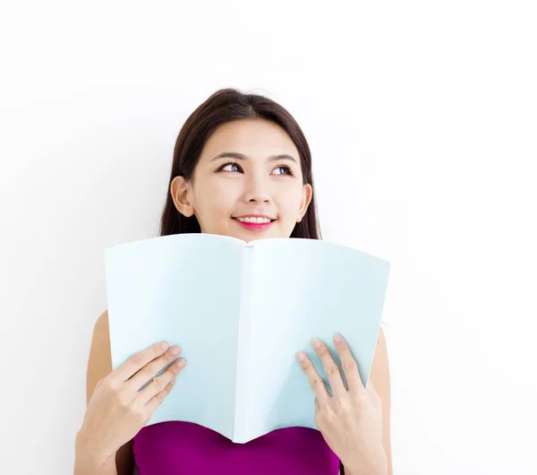 S úsměvem mladá žena čtení knihy proti bílé zdi — Stock fotografie