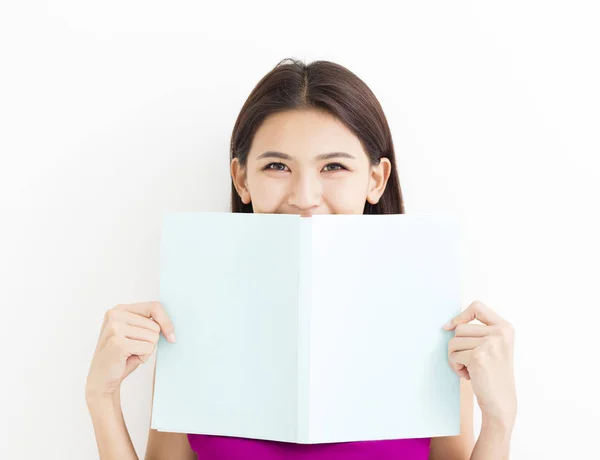 S úsměvem mladá žena čtení knihy proti bílé zdi — Stock fotografie
