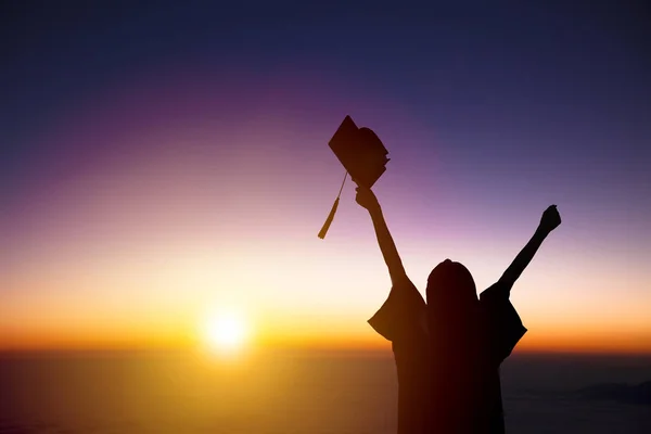 Silhouette di studente celebrazione laurea guardando la luce del sole — Foto Stock